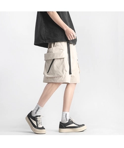 Detail shot of khaki cargo shorts with large flap pockets and black functional webbing straps
