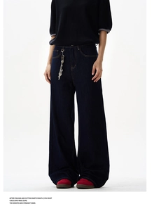 Detail of dark blue high-waisted wide-leg denim jeans with silver waist chain accessory