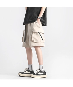 Detailed view of beige cargo shorts featuring large pockets and black zipper decoration