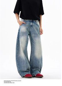 Detail of light blue washed denim jeans with whisker fading and a wide leg fit