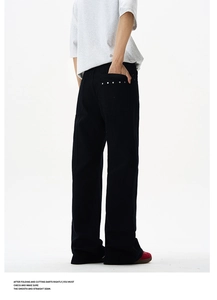 Detail view of black wide-leg trousers featuring silver metal studs on the back pocket