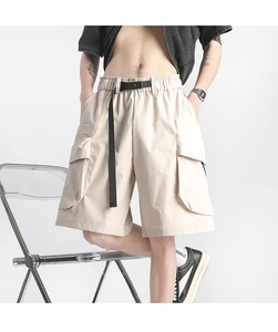 Detail of light khaki cargo shorts with utility pockets and a black nylon buckle belt