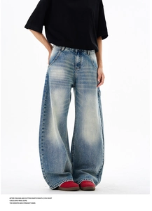 Detailed view of light blue washed denim jeans featuring whiskering and faded finish