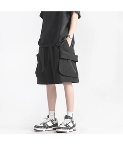 Detail view of large multi-layer cargo pockets and nylon webbing on black techwear shorts
