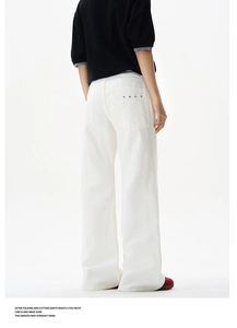 Detail shot of white wide-leg trousers featuring five silver metallic rivets on the back pocket