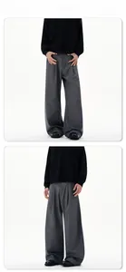 Detail of high-waisted grey wide-leg trousers featuring a single pleat and drape fabric