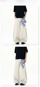 Detail of baggy curved cut pants in cream with blue checkered side fabric accent