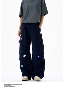 Vue détaillée de fleurs au crochet 3D brodées sur un pantalon cargo large bleu marine