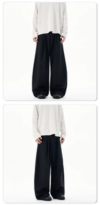 Vertical drape detail and wide-leg silhouette of black baggy trousers for men