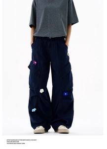 Détail d'un pantalon cargo large bleu marine avec broderies florales 3D et poches latérales