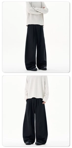 Close-up detail of baggy black trousers with pleated texture and heavy drape fabric