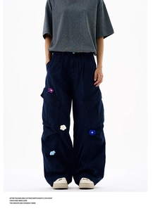 Détail du pantalon cargo bleu foncé avec des broderies de fleurs tricotées en 3D colorées