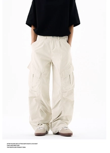 Detail view of cream cargo pants featuring large flap pockets and a loose fit silhouette