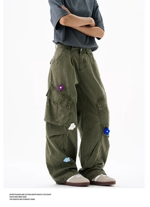 Détail d'un pantalon cargo vert armée avec écussons fleurs en tricot et poches multiples