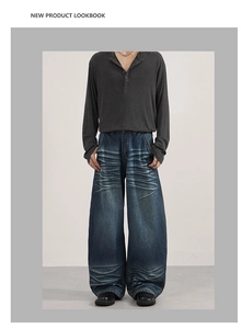 Detail of oversized dark blue wash jeans with vintage whiskers and henley long sleeve top