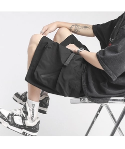 Detail view of black functional cargo shorts with adjustable straps and large pockets