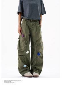 Détail d'un pantalon cargo vert olive avec des fleurs en crochet colorées artisanales