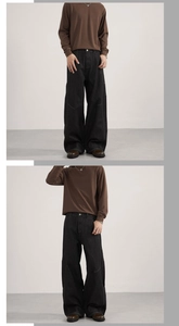 Detail of loose fit black denim jeans with contrast white stitching and brown long sleeve top