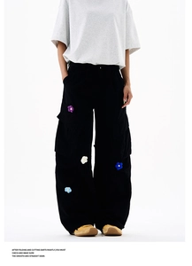 Détail de fleurs tricotées en 3D sur un pantalon cargo noir à jambes larges