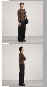 Detail of loose fit dark brown sweatshirt and black wide leg denim jeans on model