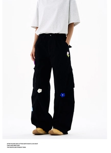 Détail d'un pantalon cargo noir avec écussons floraux 3D colorés et grandes poches latérales
