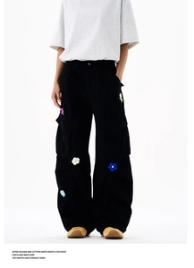 Détail de patchs de fleurs colorés au crochet sur un pantalon cargo noir large style urbain