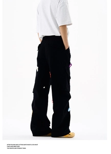 Vue détaillée des patchs de fleurs colorées au crochet sur un pantalon cargo noir large