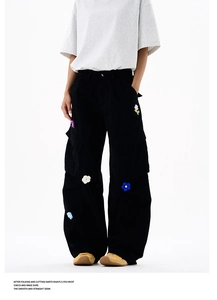 Détail du pantalon cargo noir ample avec broderies florales colorées et grandes poches