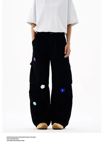 Vue détaillée des broderies florales 3D sur un pantalon cargo noir à coupe décontractée