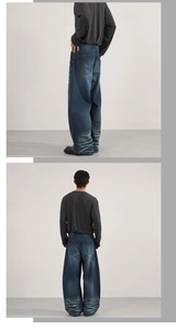 Detailed view of dark blue heavy denim baggy jeans with whiskered pleats on the cuffs