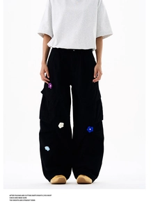 Détail d'un pantalon cargo noir avec broderies de fleurs 3D colorées et poches utilitaires