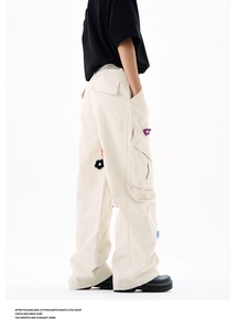 Détail des fleurs en crochet colorées sur la poche latérale du pantalon cargo blanc