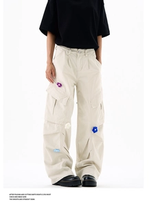 Détail de fleurs au crochet 3D et poches cargo sur un pantalon beige en coton
