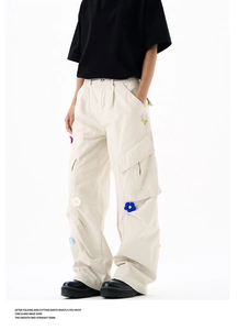 Détail d'un pantalon cargo beige ample avec broderies florales 3D et poches latérales