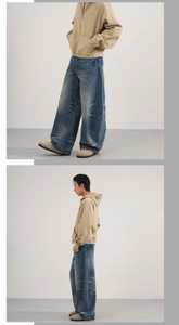 Detail of vintage loose-fit wide-leg jeans with cat whiskers wash and a khaki hooded jacket