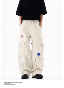 Détail de la broderie florale 3D sur un pantalon cargo beige à plusieurs poches