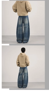 Detail view of baggy distressed denim jeans with heavy whiskering and street style fit
