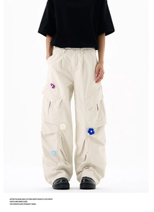 Détail de fleurs en crochet 3D brodées sur un pantalon cargo beige à grandes poches