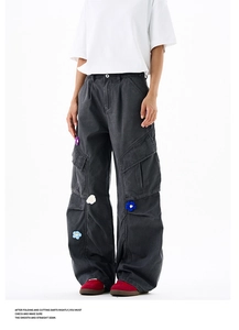 Gros plan du pantalon cargo gris foncé avec broderie florale 3D et une grande poche latérale