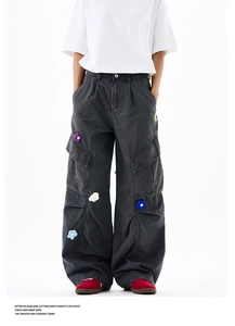 Détail d'un pantalon cargo gris foncé avec broderies de fleurs 3D colorées au crochet