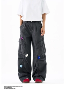 Détail de ce pantalon cargo gris foncé avec fleurs colorées en crochet sur les poches