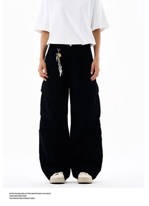 Detail view of black cotton cargo pants featuring large side pockets and silver waist chain