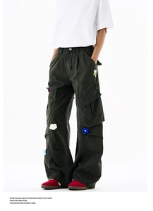 Détail macro du pantalon cargo avec broderies florales 3D et poches latérales