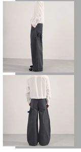 Dettaglio dei pantaloni cargo grigio scuro larghi con grandi tasche laterali e passanti