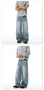 Detail of light blue washed baggy jeans with vintage distressed finish and wide leg fit