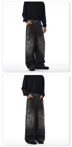 Detail of baggy black washed denim jeans featuring white paint splatter and loose fit design