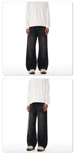 Detailed view of wide-leg denim jeans featuring white paint splatter on dark wash fabric