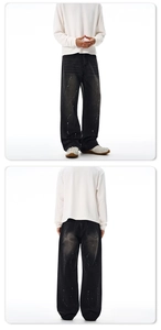 Detail view of baggy black jeans with white paint splatter and loose-fit silhouette design