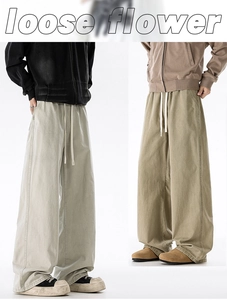Detail view of men's loose wide-leg pants with drawstring waist in grey and khaki tones