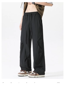 Detail view of black quick-dry parachute pants with elastic drawstring waist and street style
